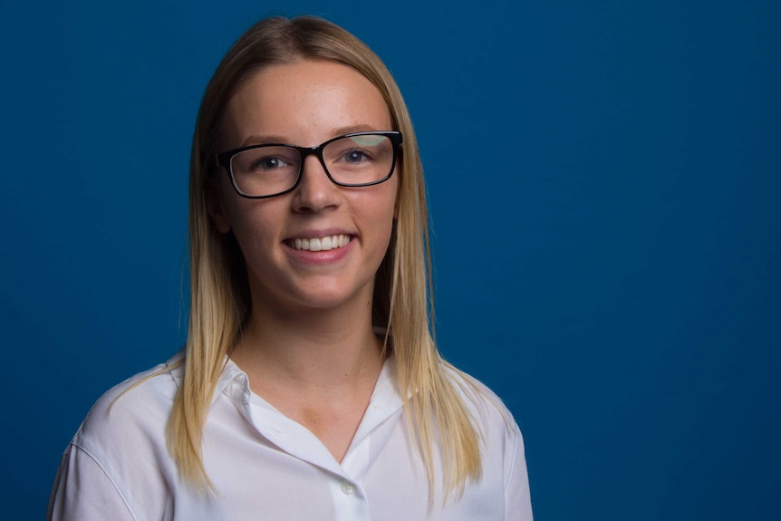 A portrait of Sarah against a blue backdrop.