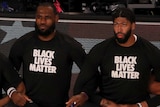 Lakers players, including LeBron James and Anthony Davis, take a knee while arm in arm, wearing a "BLACK LIVES MATTER" shirt