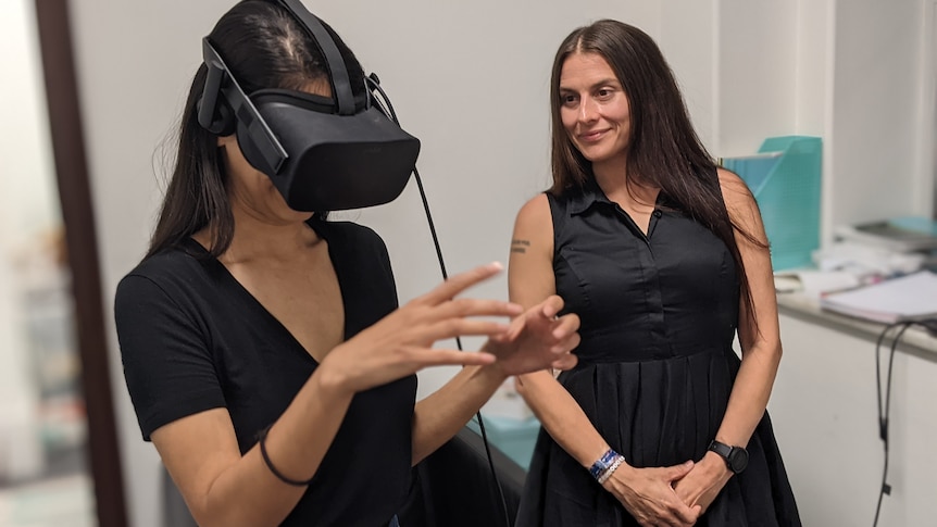 All in the Mind presenter Sana Qadar has a VR headset on and is watched by psychologist Corrie Ackland