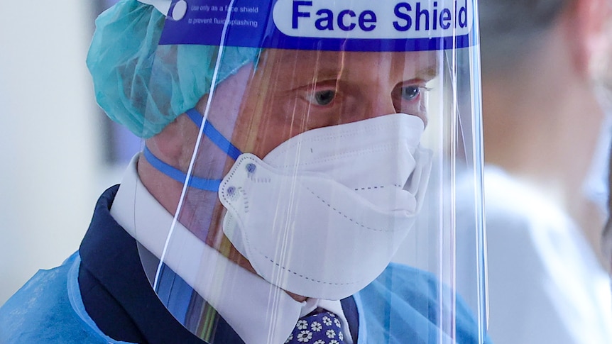 Michael Kretschmer visits a COVID ward wearing a mask and face shield.