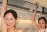 Rebecca Sy and three colleagues reach up to the overheard luggage compartments.