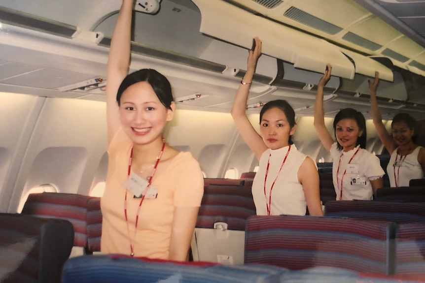 Rebecca Sy and three colleagues reach up to the overheard luggage compartments.