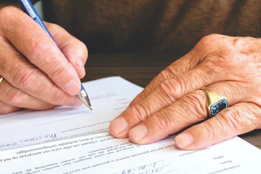 A hand signs a document. 