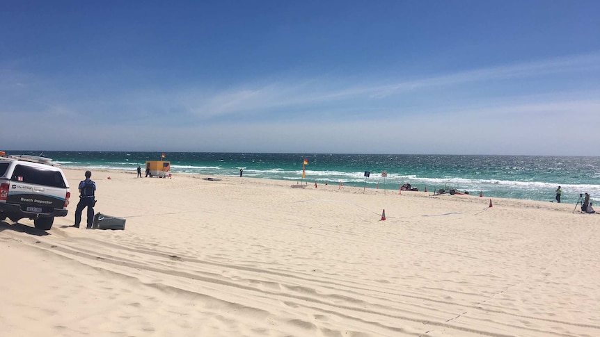 Wide shot of Trigg Beach showing police tape and lifesavers' flags.