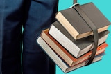 A stack of hardback school-books tied together and carried with a belt.