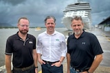 three men standing in front of large cruise ship