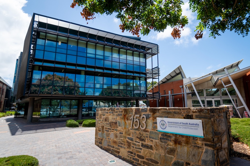 Glass building with stone wall that depicts sign saying Government of South Australia Department of Child Protection