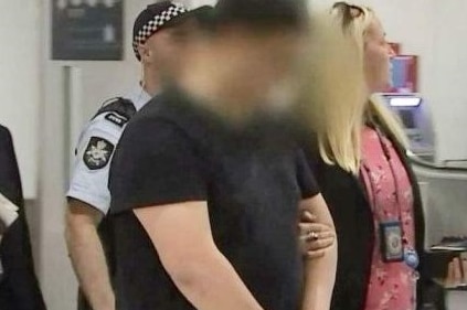 man at airport being escorted by police