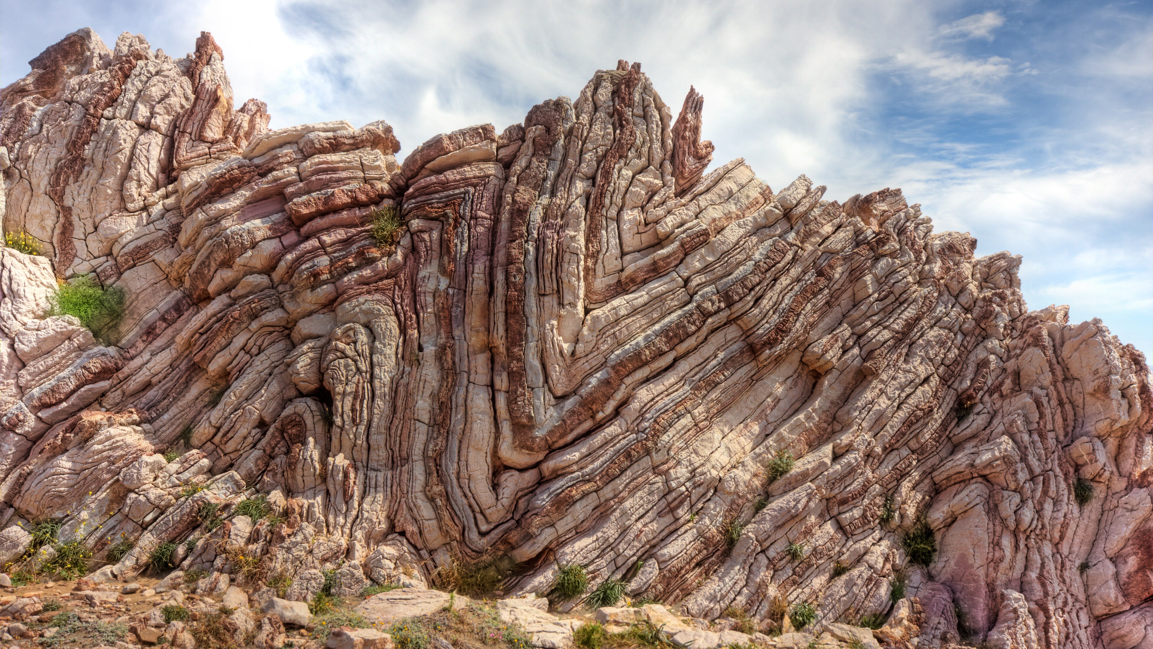 A cross-section of a cliff showing wavy layered rocks