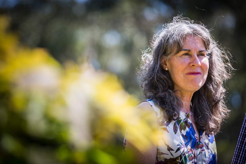 A woman stands in a garden.