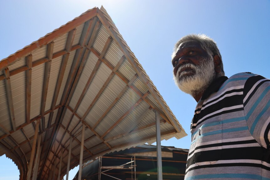 an aboriginal man wearing a striped shirt looking into the distance
