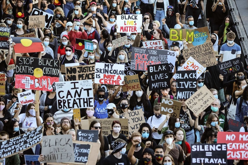 A large crowd of people with masks holding Black Lives Matter signs.