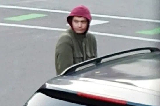 Surveillance camera footage of a man in a hoody getting into a car