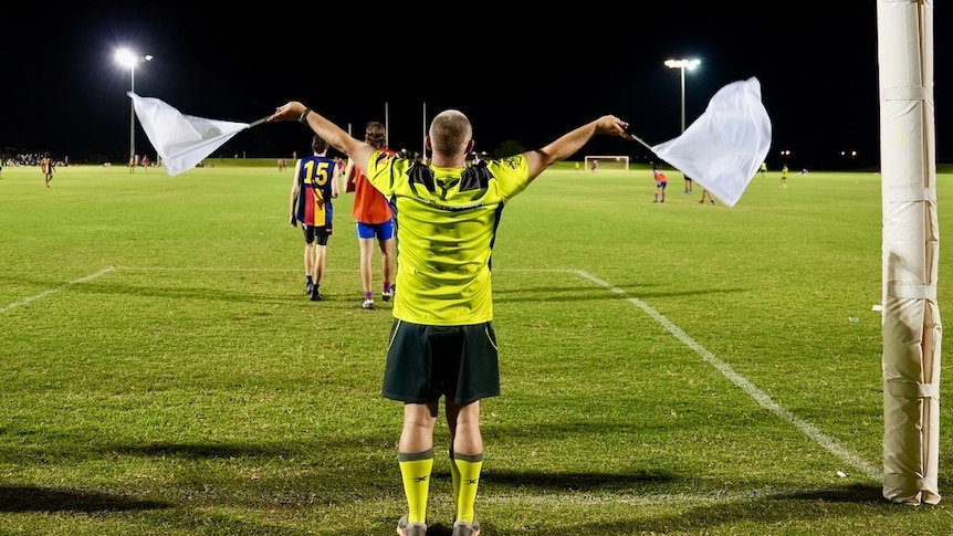 An umpire waves flags in football goals