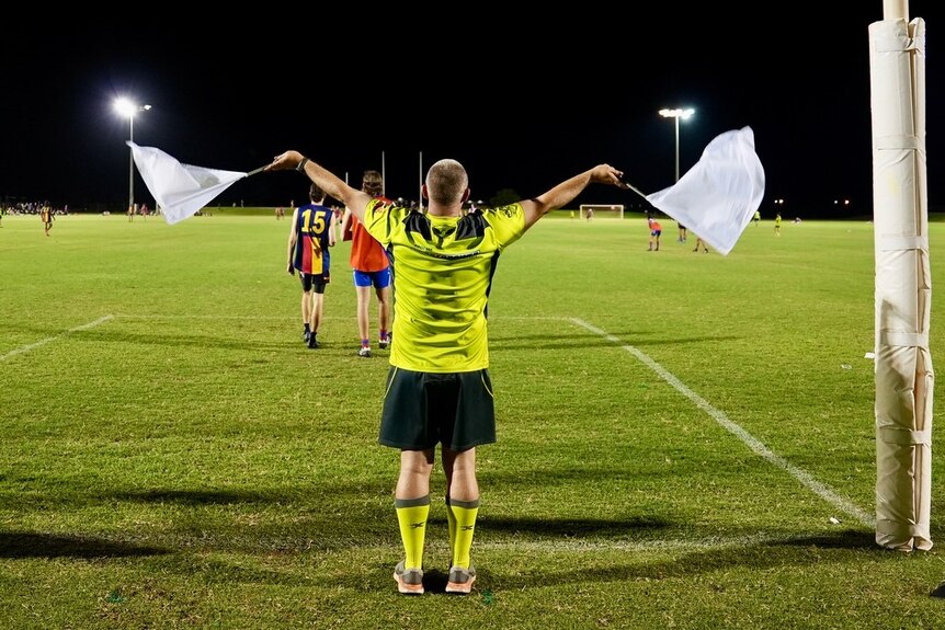 An umpire waves flags in football goals