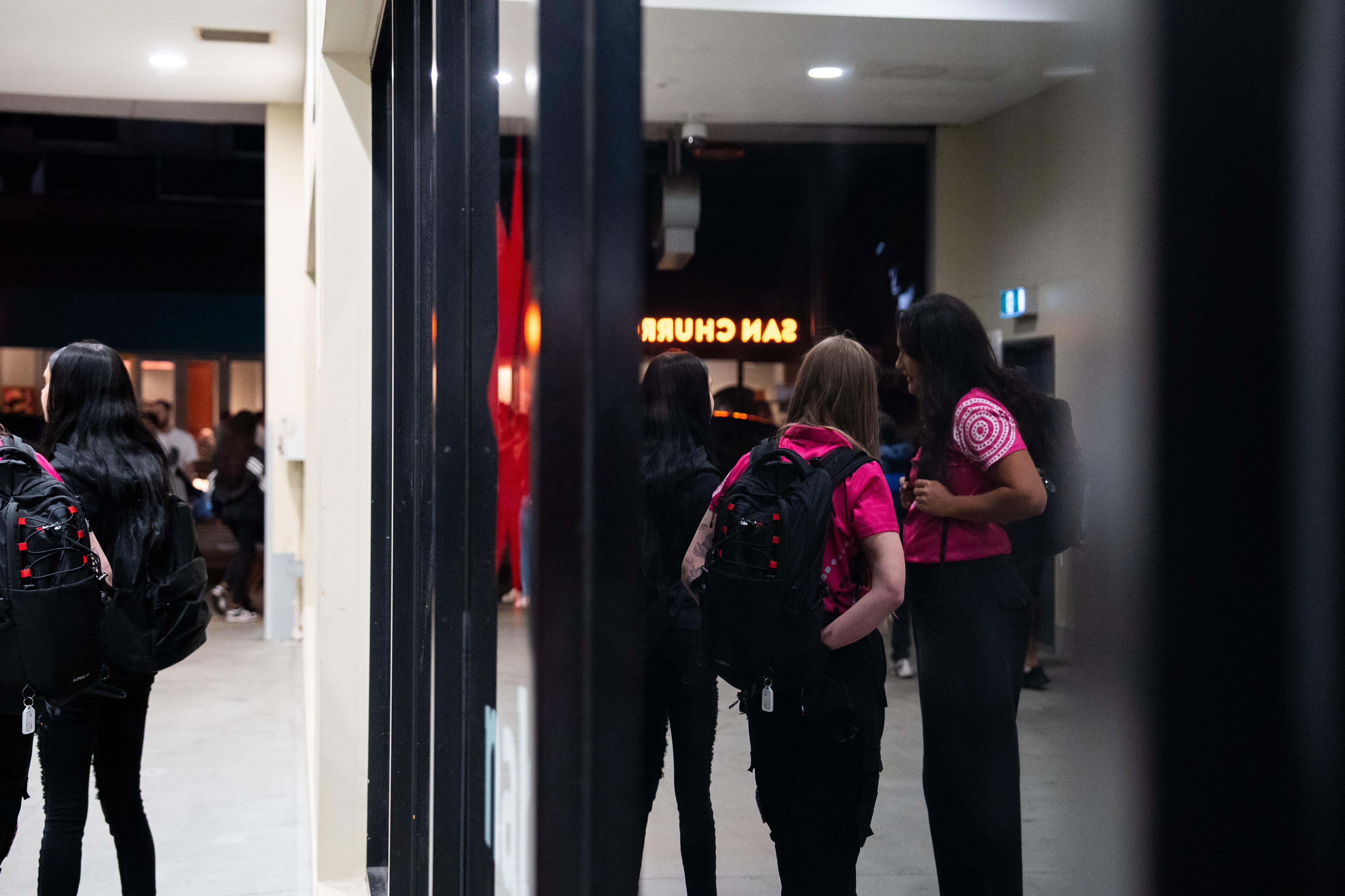 Two women who are youth workers stand in a busy Perth street at night 