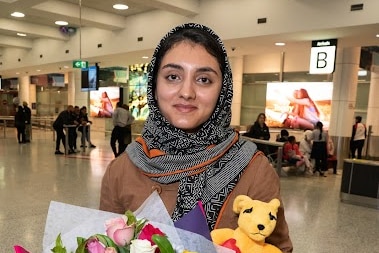 A woman in a headscarf hold a bouquet of flowers and a boxing kangaroo toy 