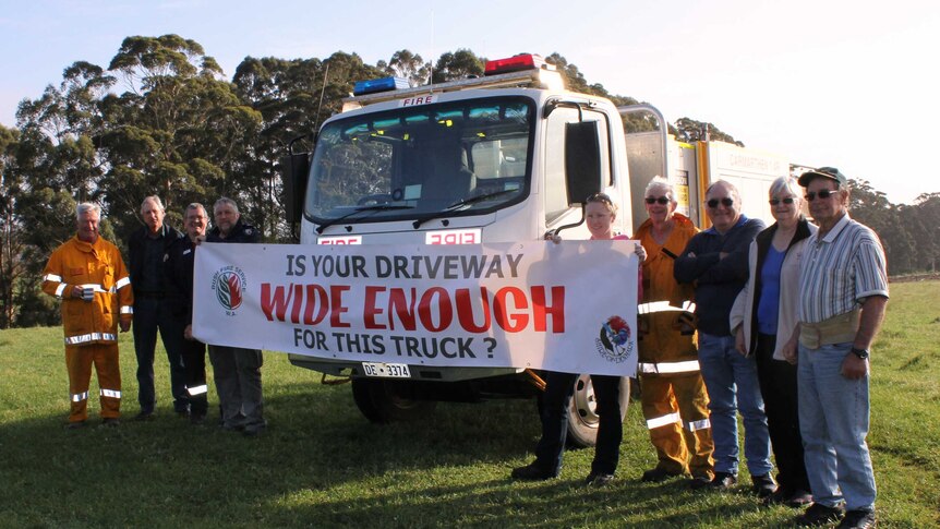 Firefighters with the Carmarthen BFB hold up a sign, reading 'Is your driveway wide enough for this truck?'