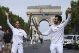 A man and woman dressed in white hold two large torches in Paris
