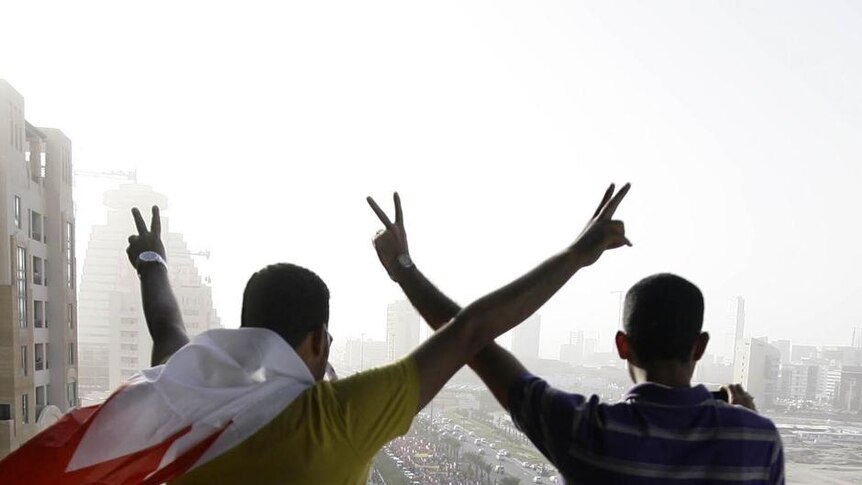 Bahraini youths with national flag draped around their necks show the V-for-victory sign