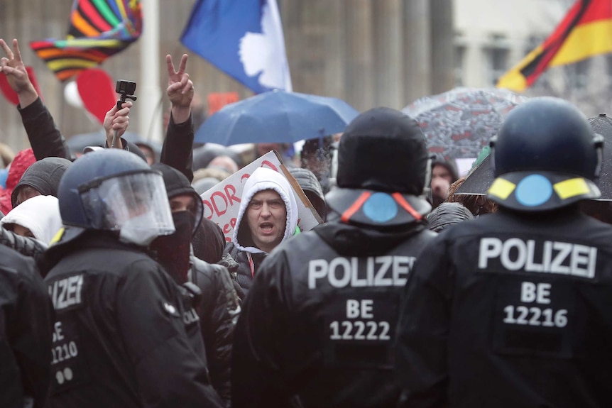 A protester shouts as police officers.