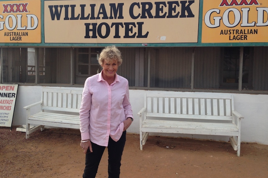 Heather Ewart dressed in a pink shirt and dark jeans stands outside the William Creek Hotel.