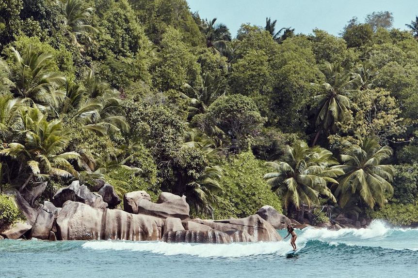 Female surfing with a beautiful island backdrop 