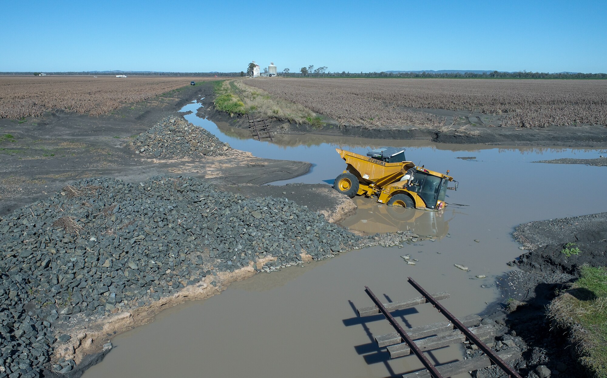 Heavy plant machinery partly submerged in flood water near Pampas, Queensland, July 2022.