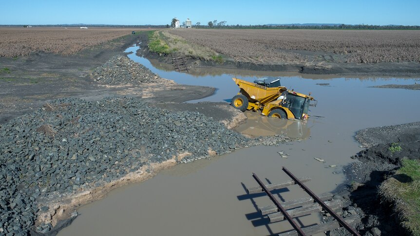 Heavy plant machinery partly submerged in flood water near Pampas, Queensland, July 2022.