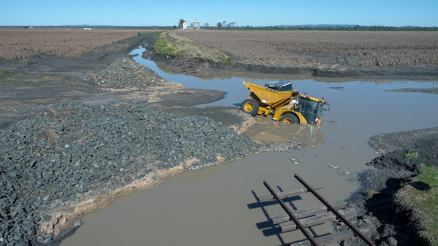 Heavy plant machinery partly submerged in flood water near Pampas, Queensland, July 2022.