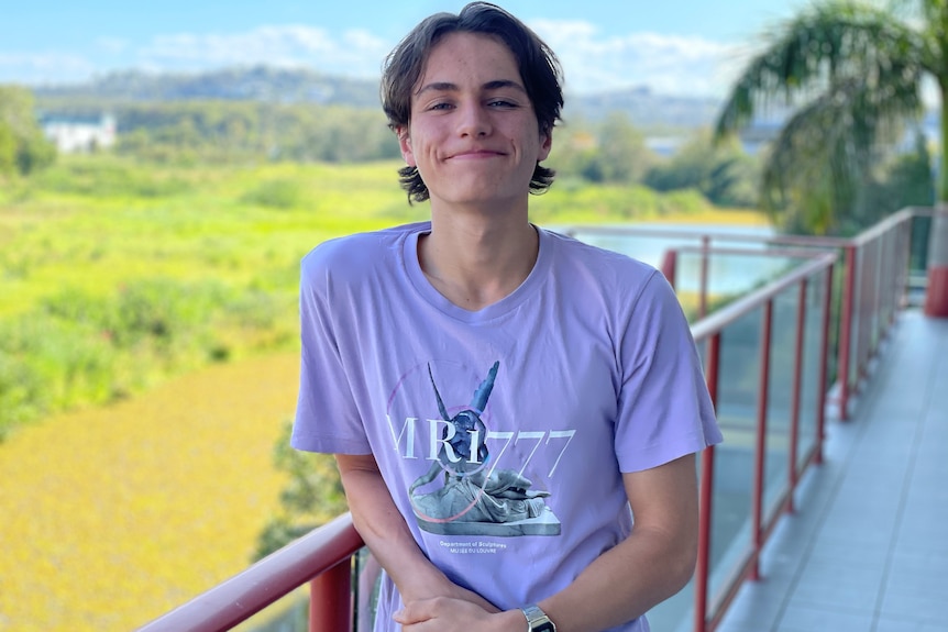 a young man stands with hands on hips near a coastal cliff