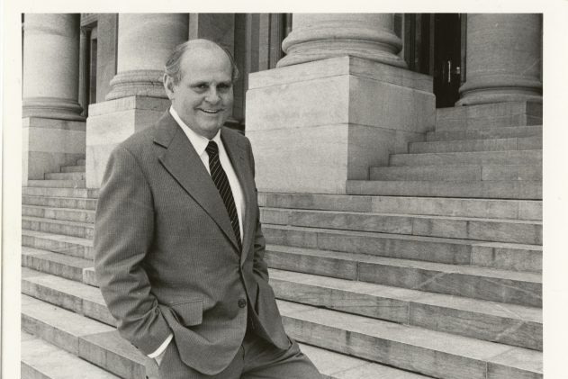 Black and white photo of man standing on step of building