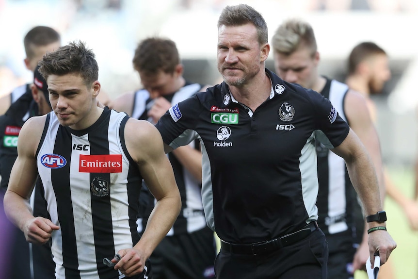 Nathan Buckley puts his arm around the shoulder of one of his players.