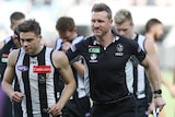 Nathan Buckley puts his arm around the shoulder of one of his players.
