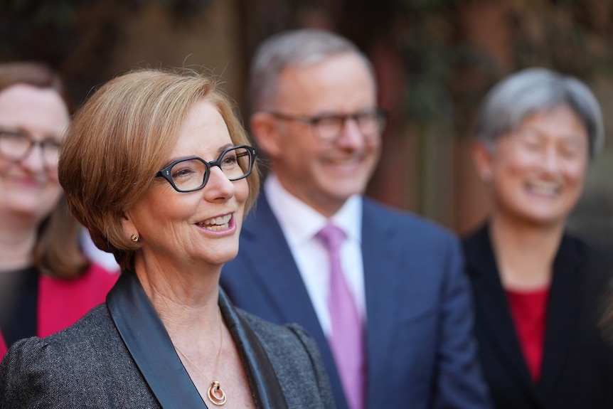 Julia Gillard smiles while standing alongside Anthony Albanese and Penny Wong.