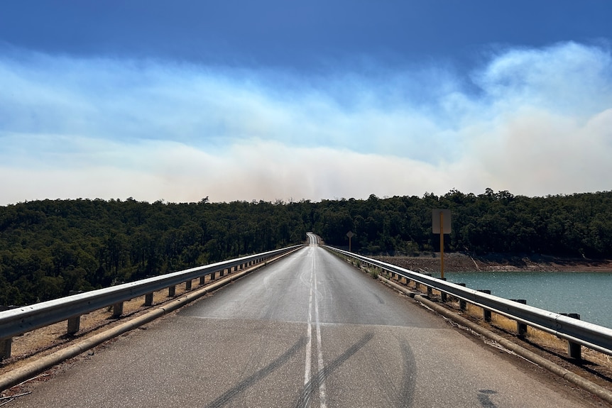 The bridge running over the Waroona dam with smoke from the fire in the background.