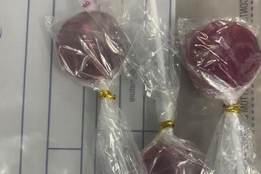 Small lollipops in wrappers on background of a police notebook. There is a WA police logo in the picture