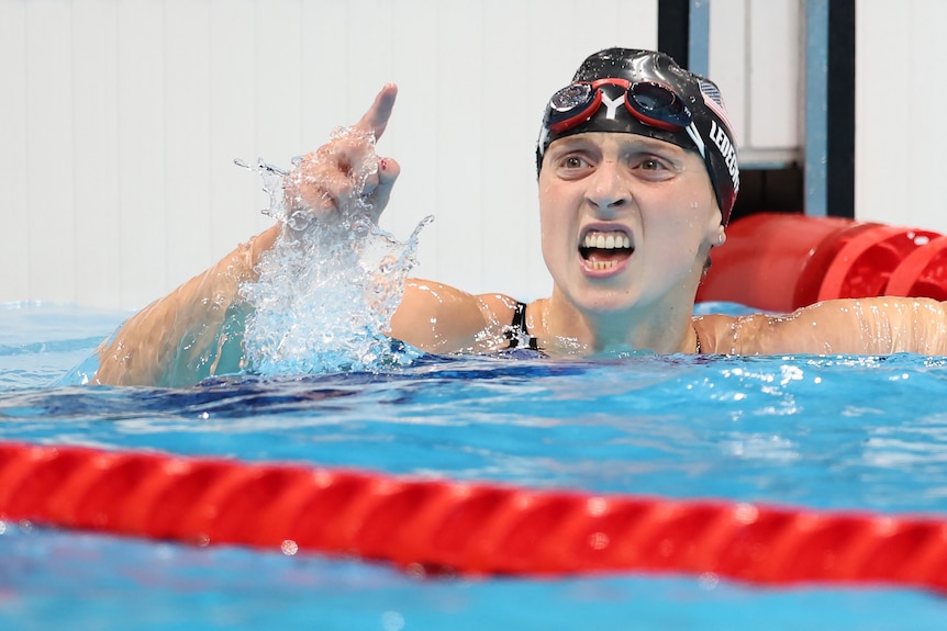 A woman in a pool wearing a black swimming cap