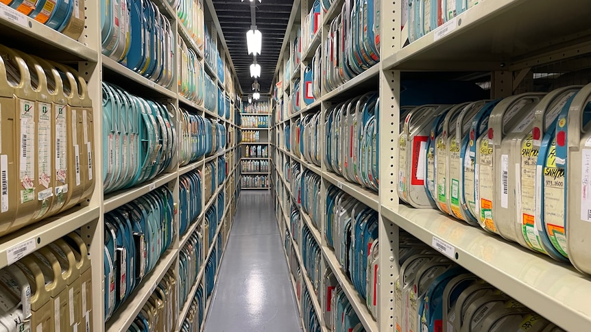 A long corridor in a warehouse with high shelves filled with unidentifiable objects.