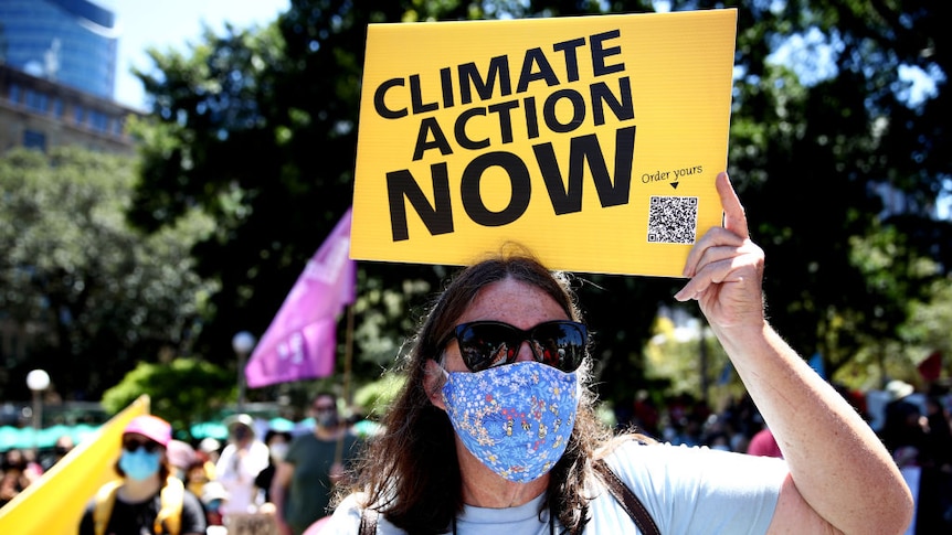 A woman protester holds up a sign saying 'climate action now'