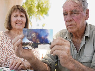 A woman and a man holding a photo of a fire.