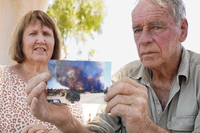 A woman and a man holding a photo of a fire.
