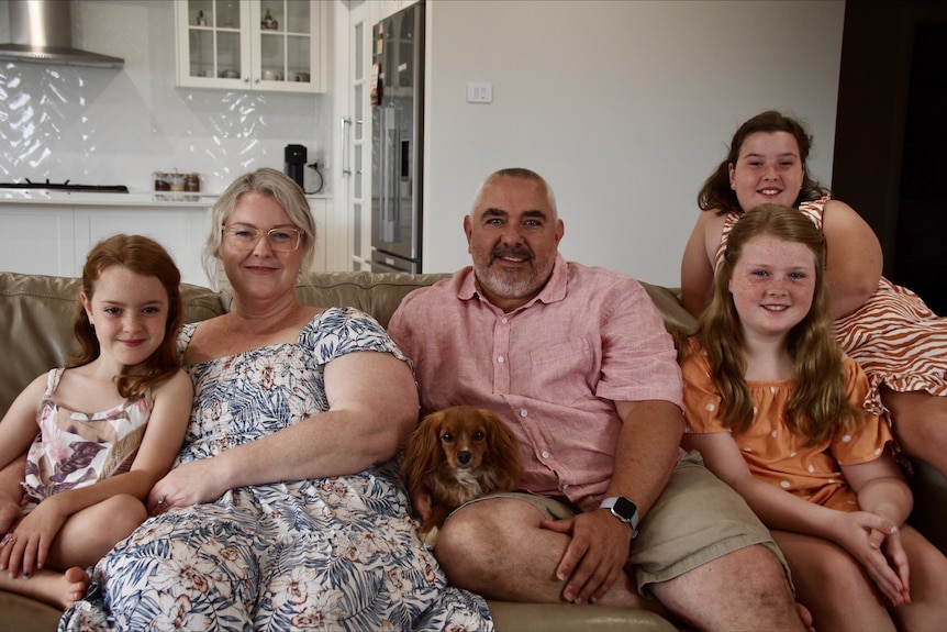 The Buckley family sit in their lounge smiling in their new home. 