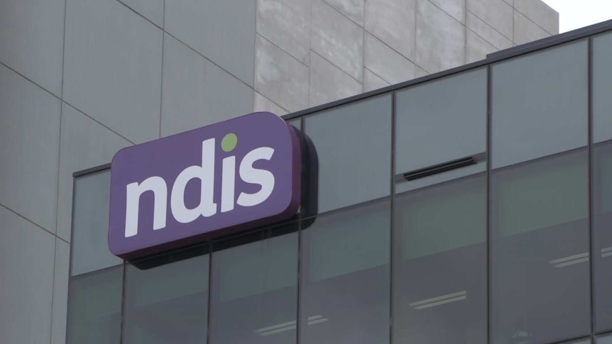 A purple NDIS sign on the side of an office building.