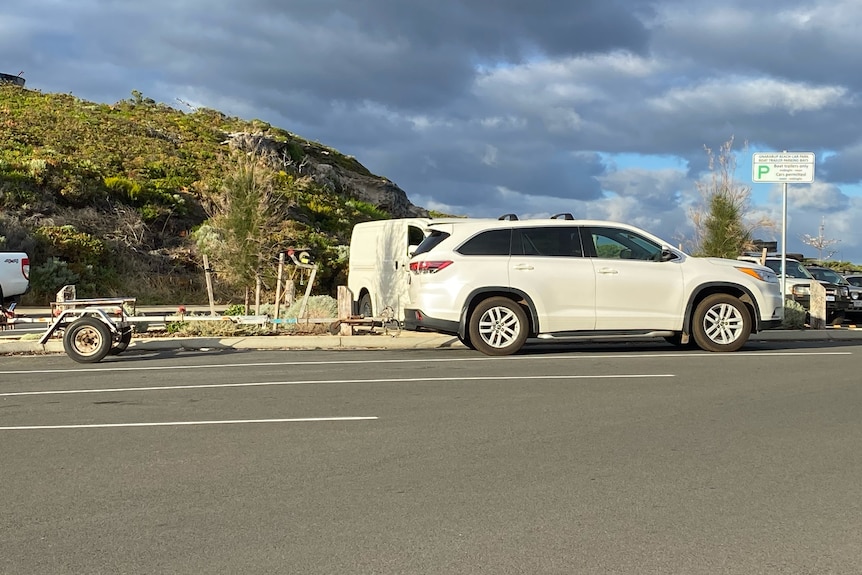 A large white car and trailer in a car park 