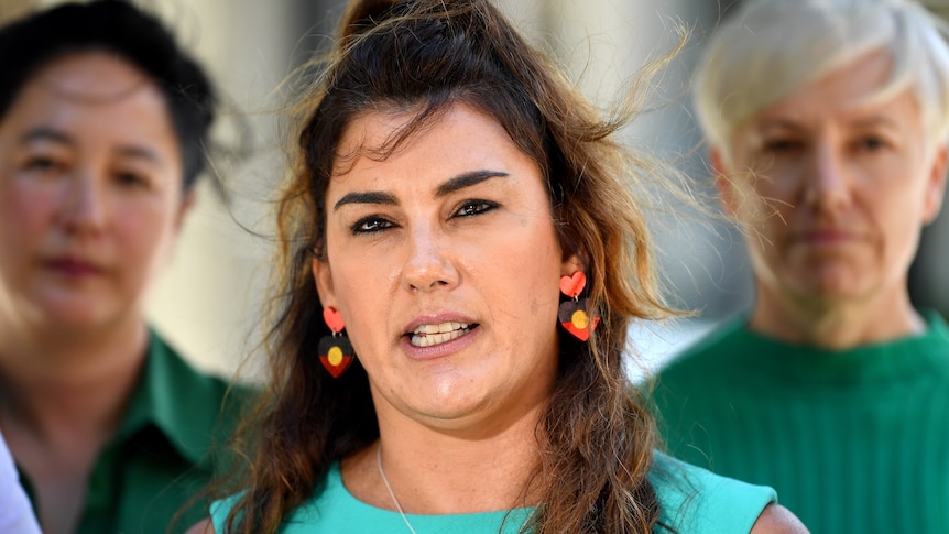 Lidia speaks at a press conference whikle wearing Indigenous flag earring.