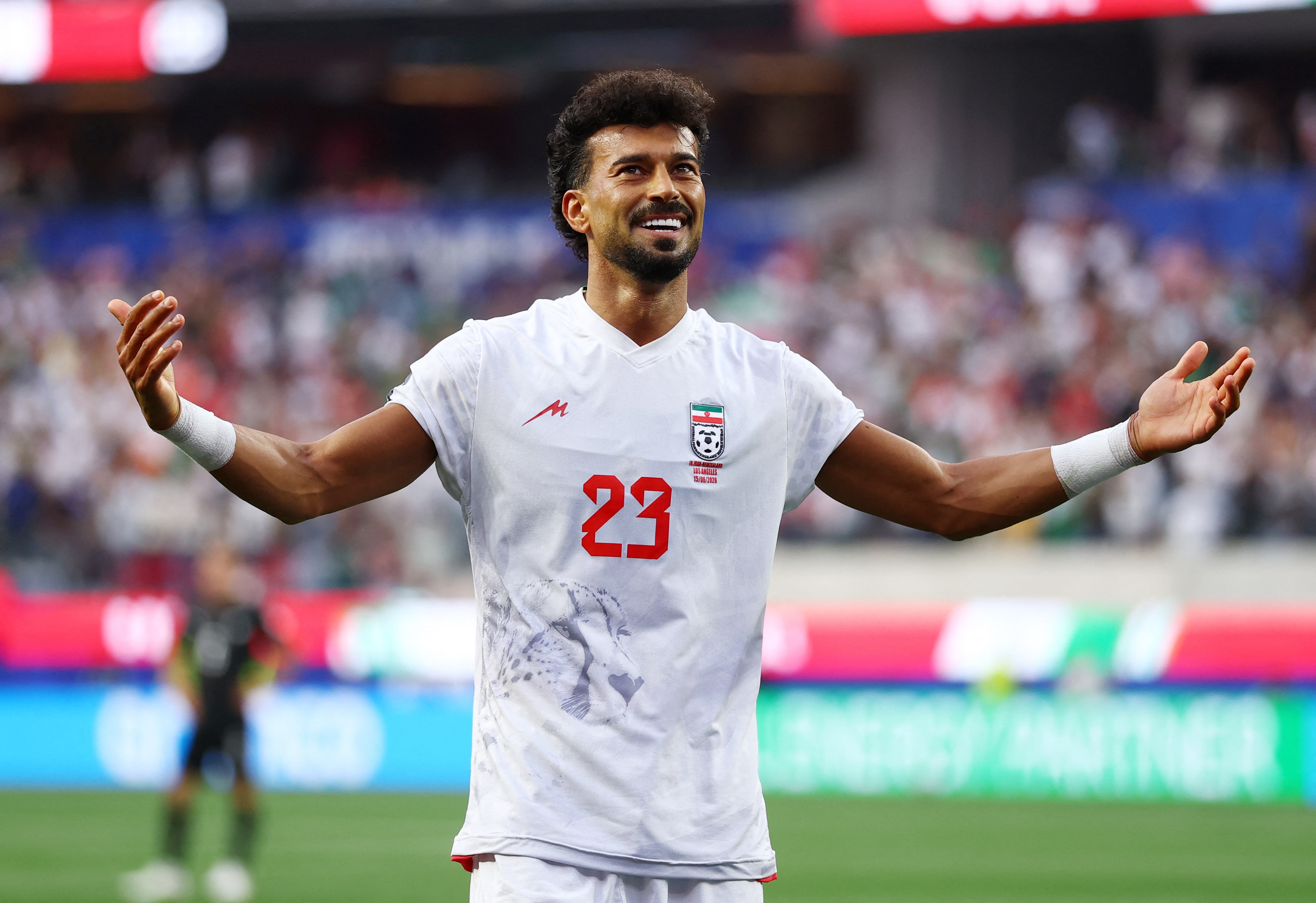 Iran player Ramin Rezaeian smiles and holds arms outstretched after scoring a goal