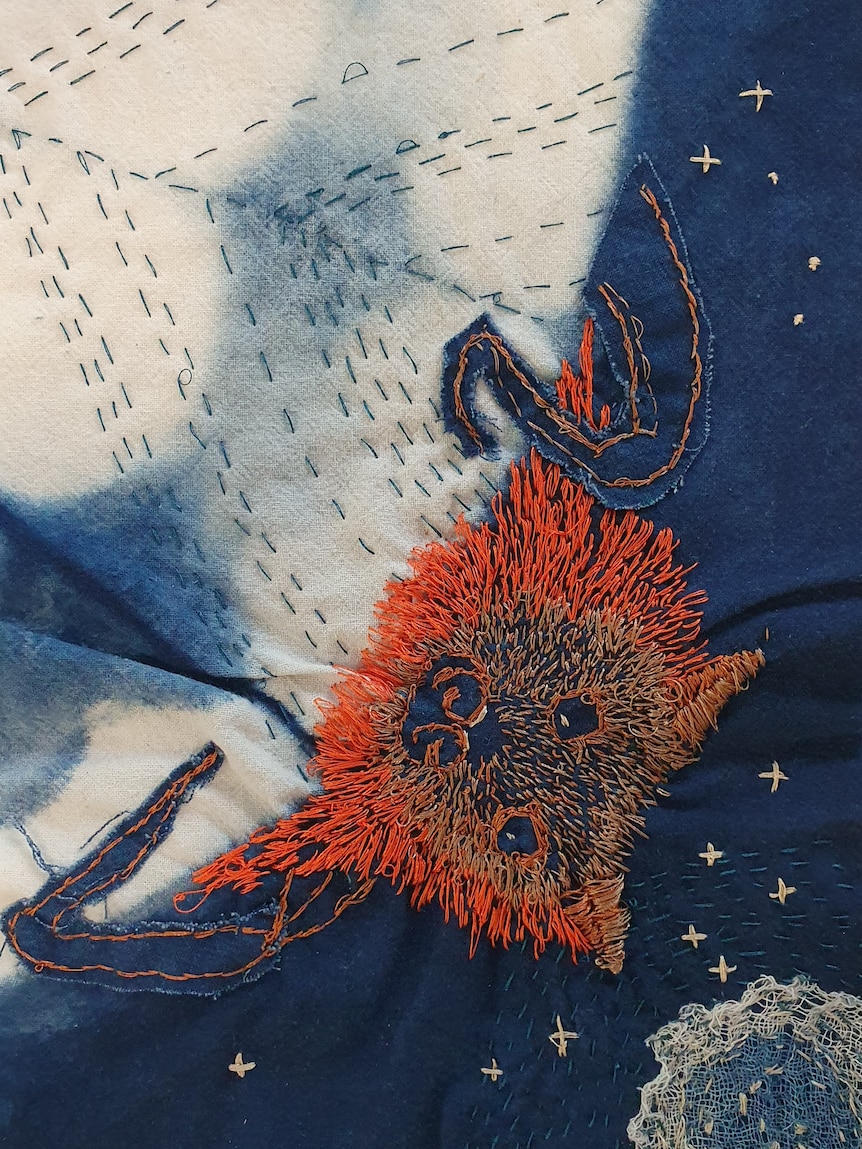 A piece of quilt with a fruit bat stitched into it.