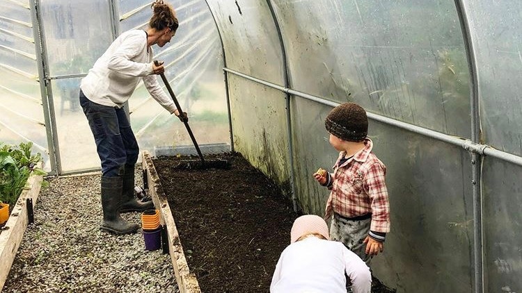 woman and two small children gardening