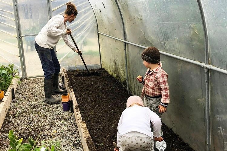 woman and two small children gardening